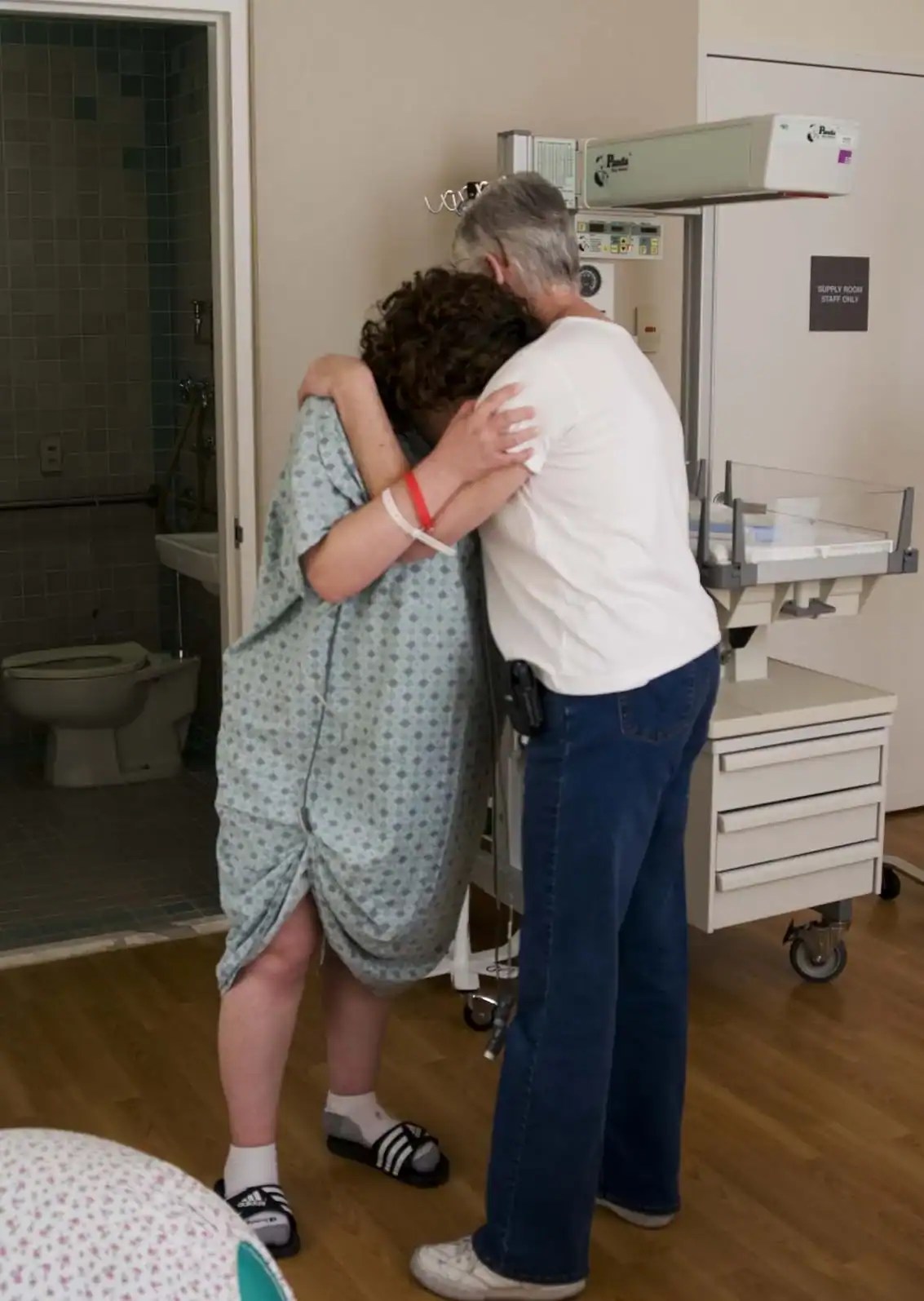 Doula and client slow dancing during labor in hospital room.