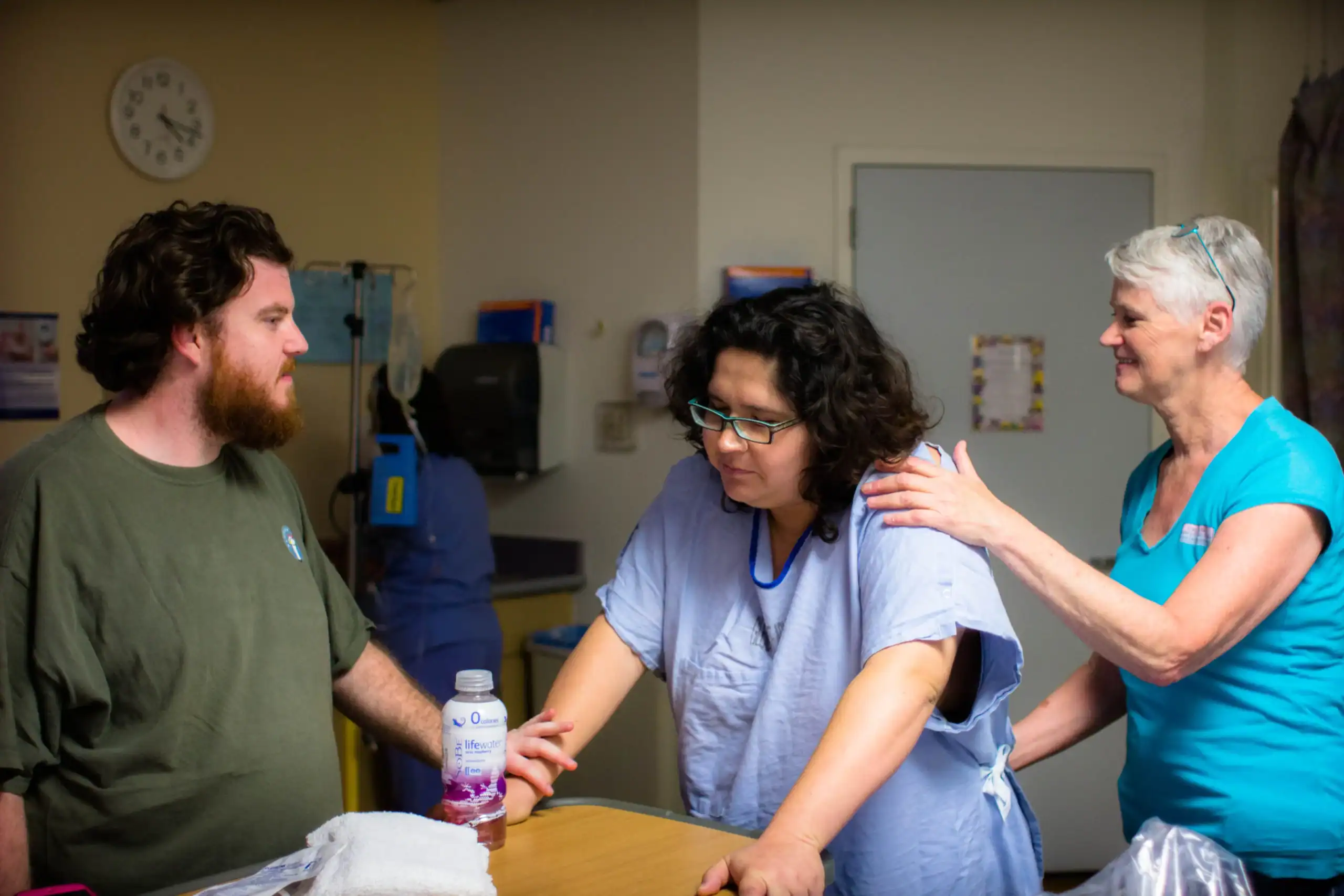 Doula providing emotional support to a mother during labor in a hospital setting.