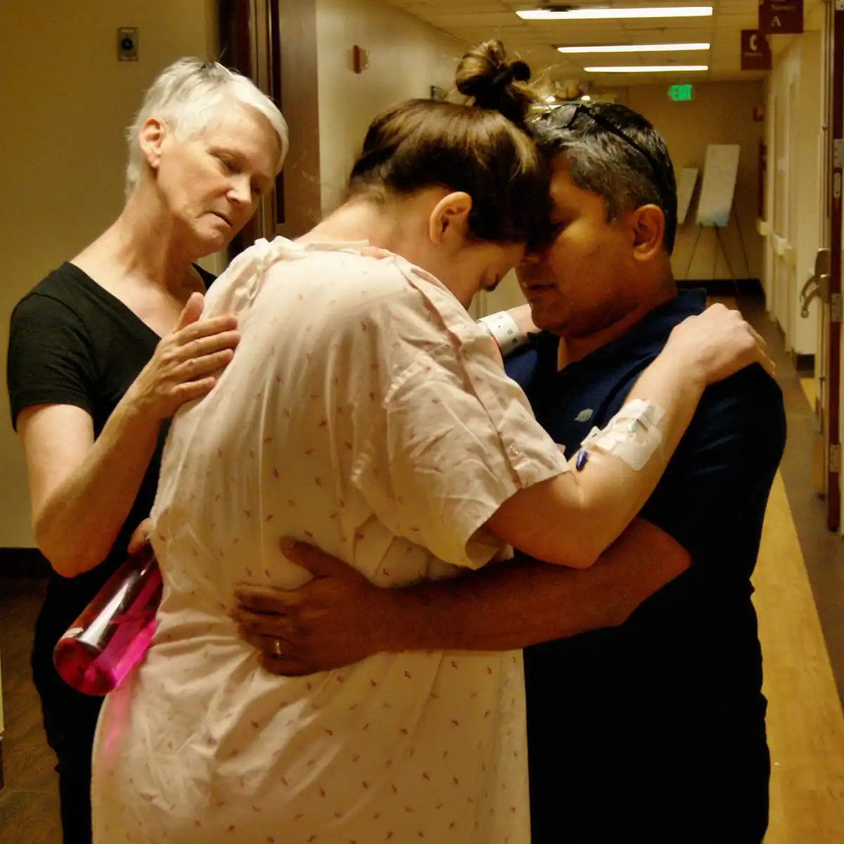 Supportive doula and partner comforting a woman during labor in hospital.