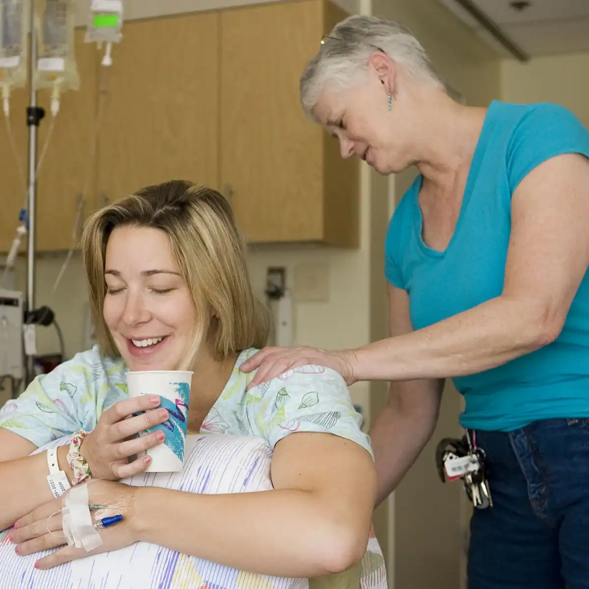 Supportive doula comforting a new mother with partner during labor and delivery.