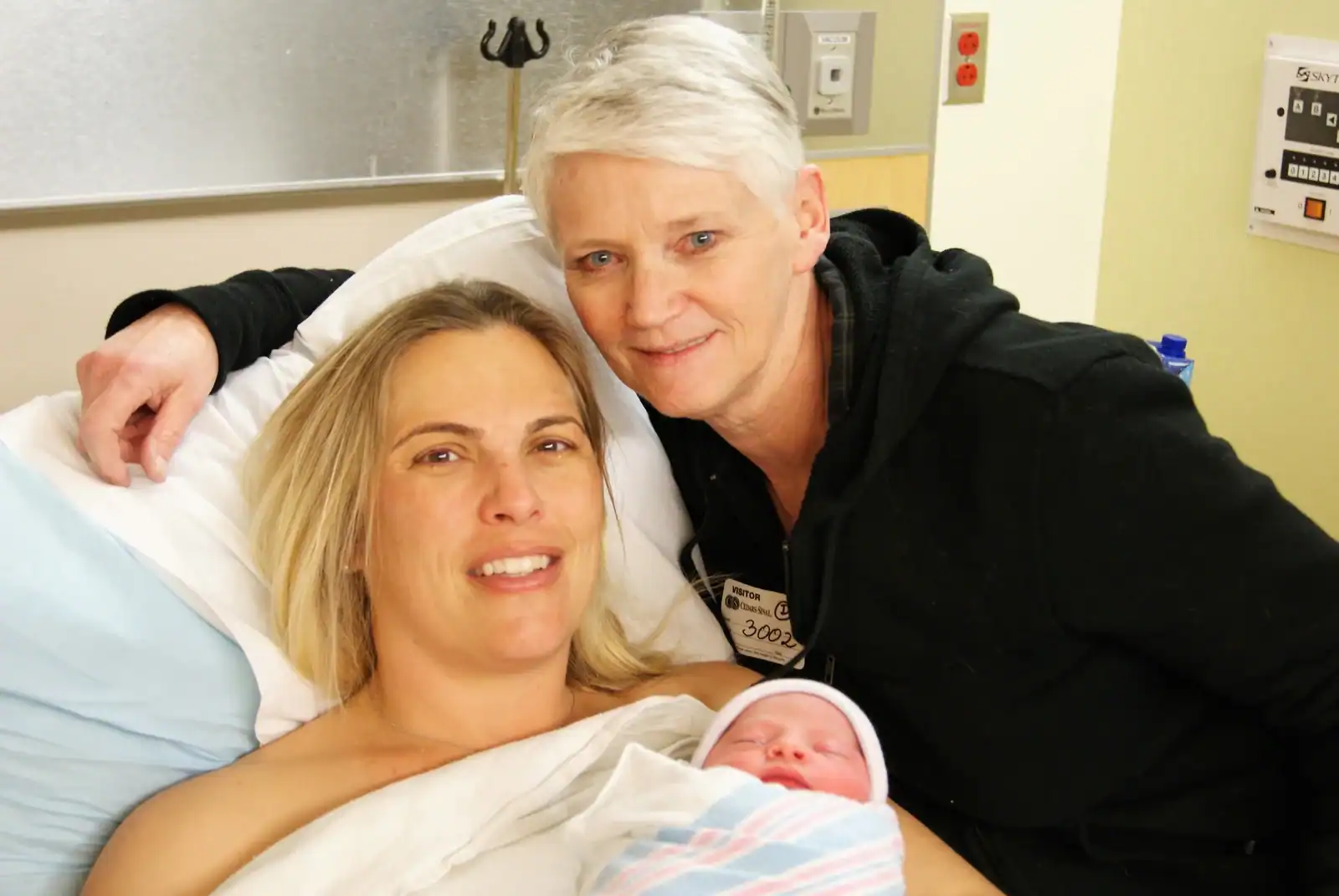 Comfortable hospital scene with a new mother, her partner, and her newborn baby after childbirth.