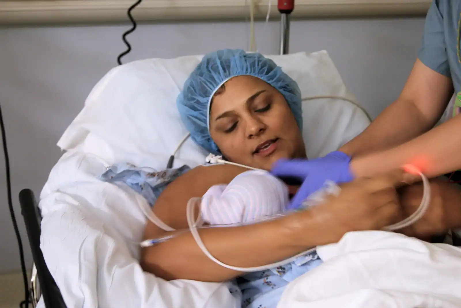 Postpartum doula providing emotional support to new mother in hospital bed.
