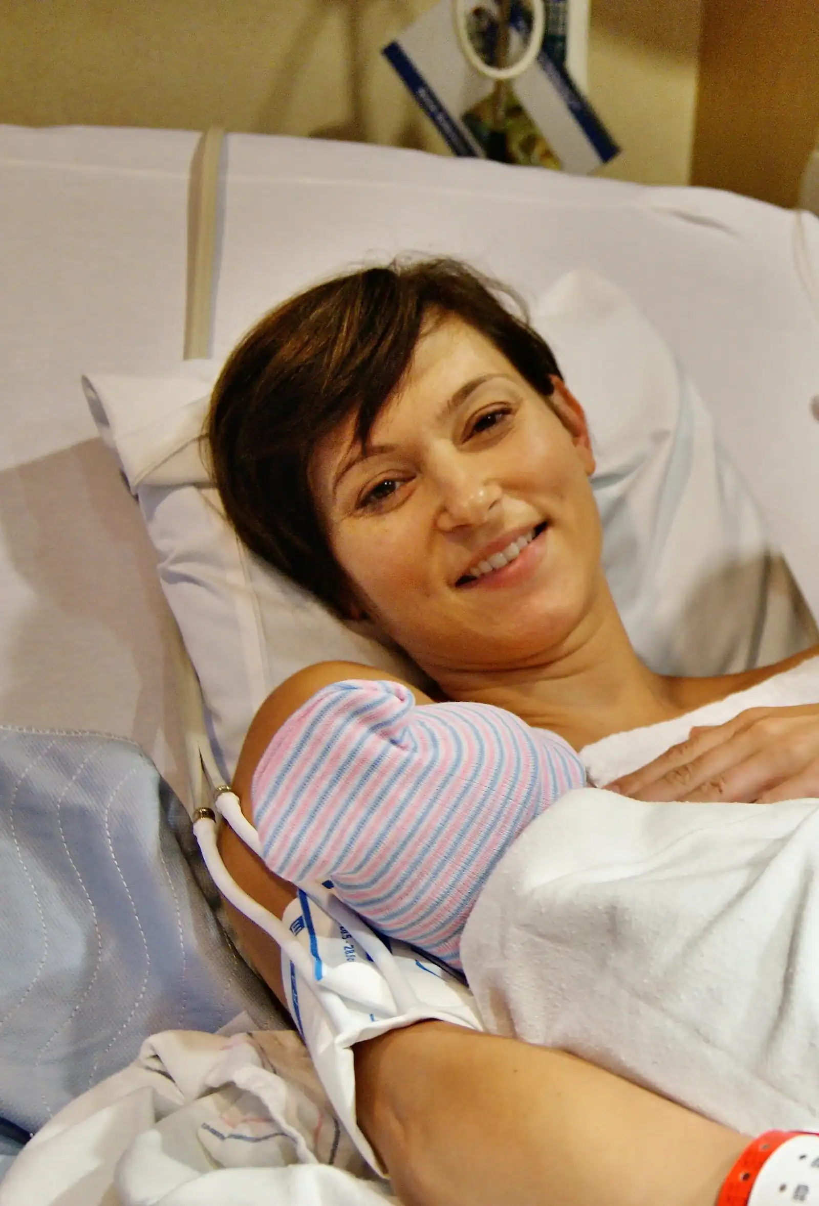 Mother holding her baby after childbirth, in hospital setting.