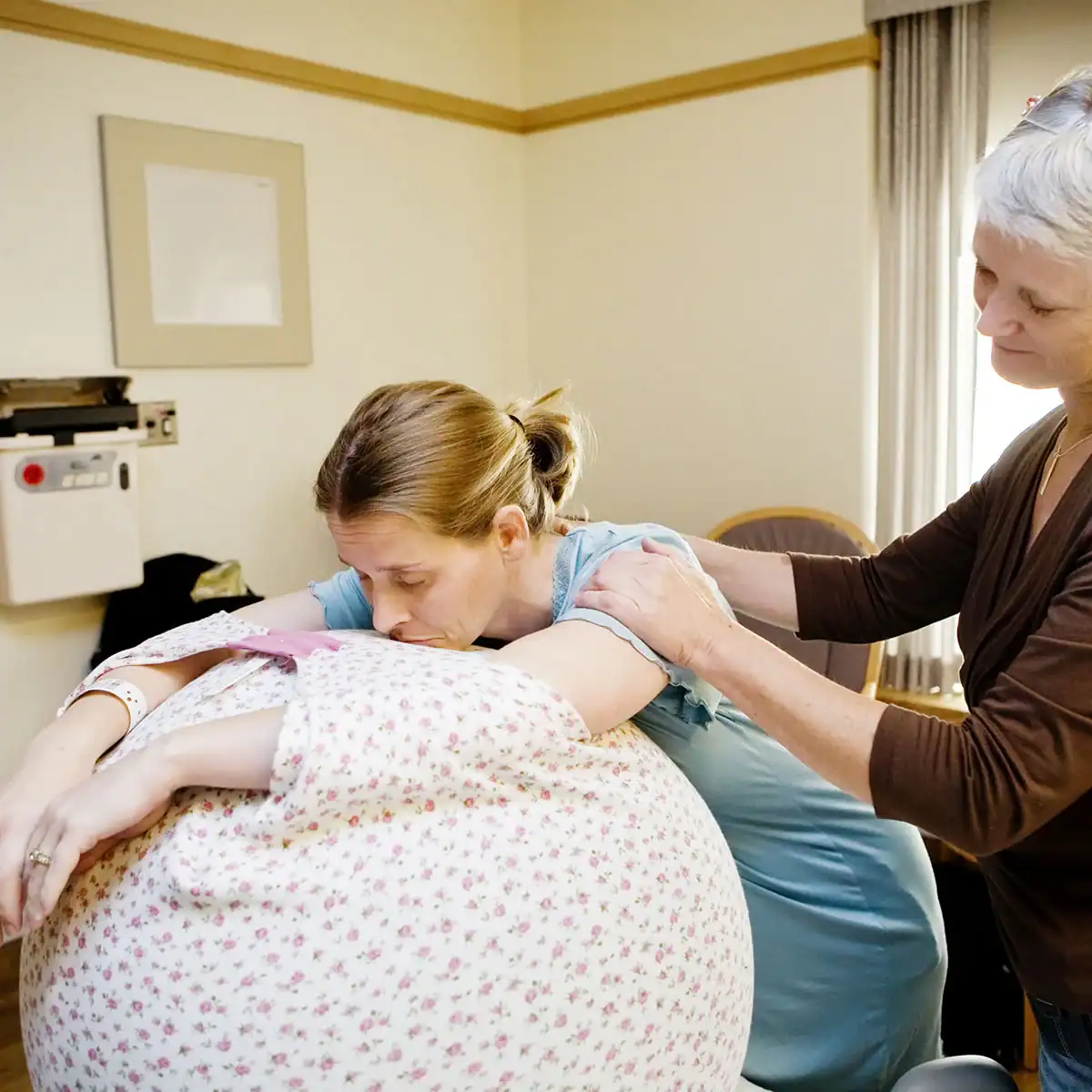 Laboring woman using a birth ball during childbirth with doula assistance.