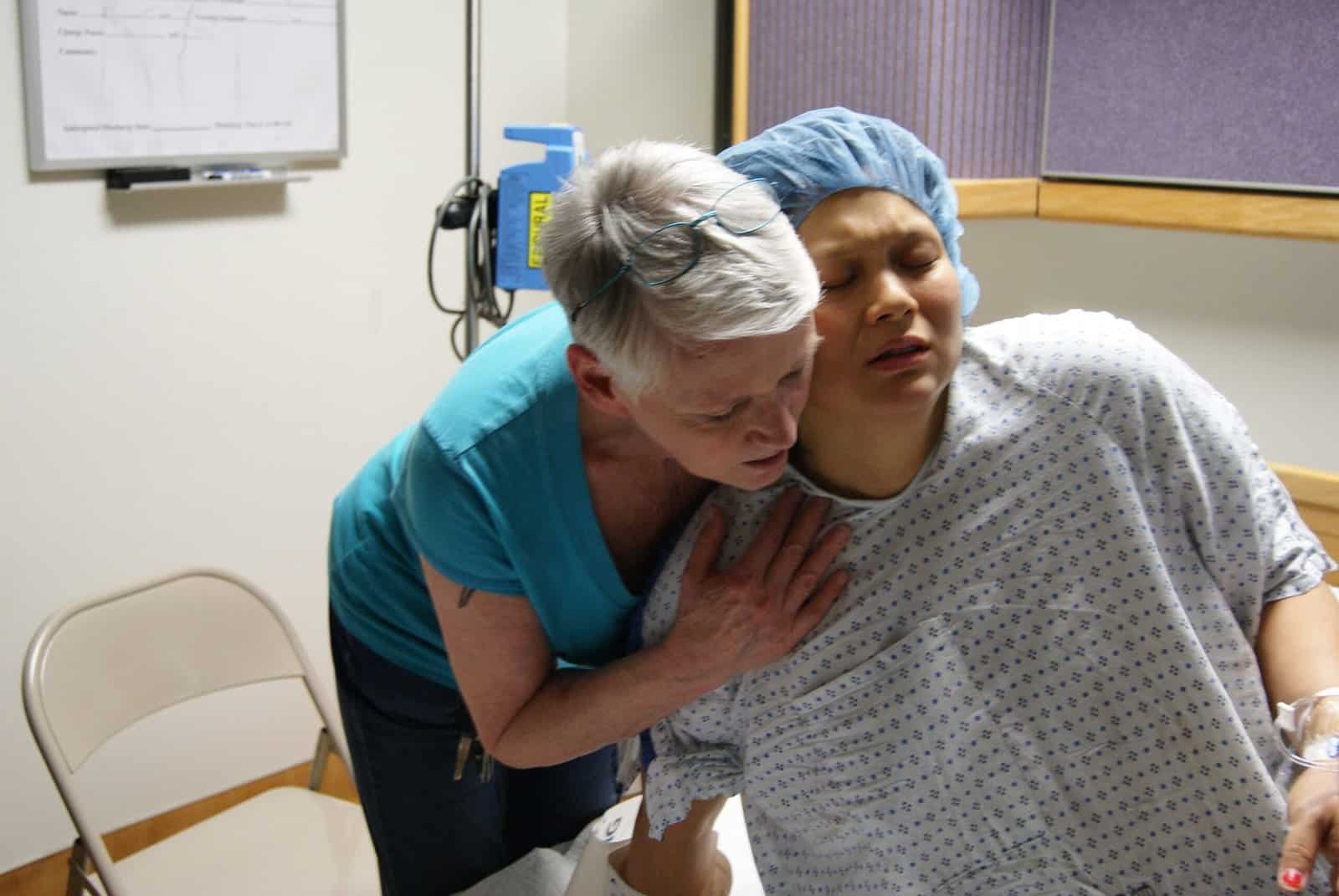 Birth doula comforting a laboring client through a contraction during a hospital birth.