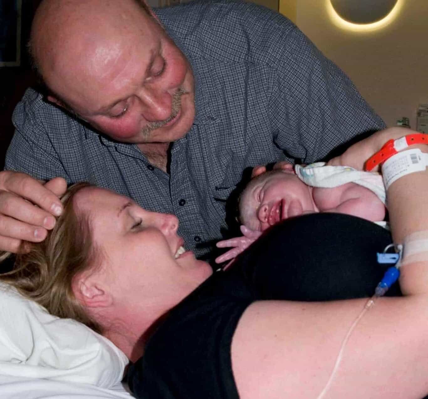 Happy couple with newborn baby after vaginal hospital birth.